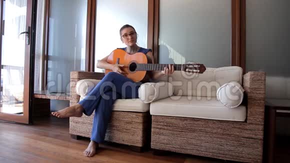 一个年轻女孩坐在沙发上弹吉他视频的预览图