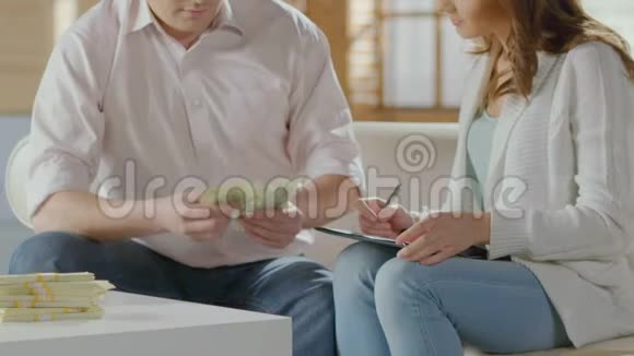 男人数着美元把它们放在桌子上拥抱女人买房子视频的预览图