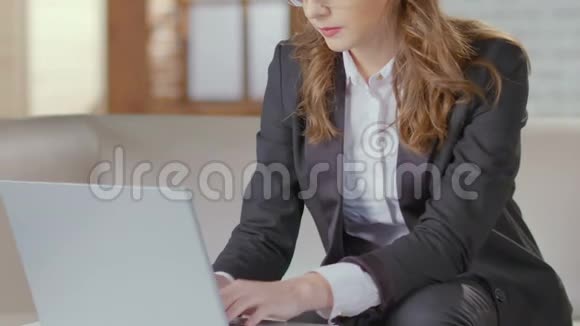 女商人坐在沙发上用笔记本电脑打字准备开会视频的预览图