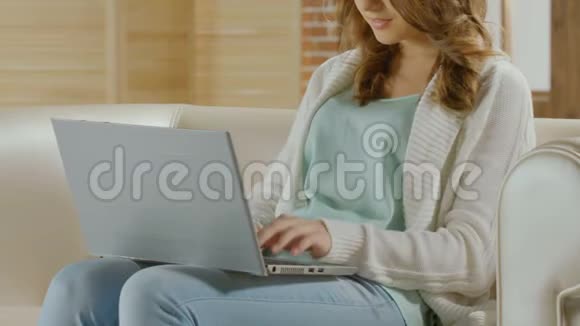 年轻女子坐在沙发上和男朋友在笔记本电脑上聊天放松一下视频的预览图