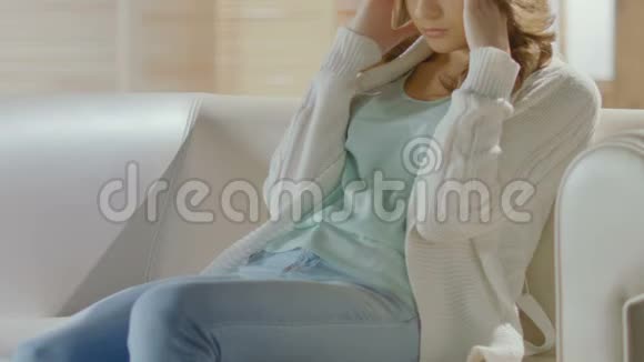 布鲁内特女孩坐在沙发上头痛偏头痛视频的预览图