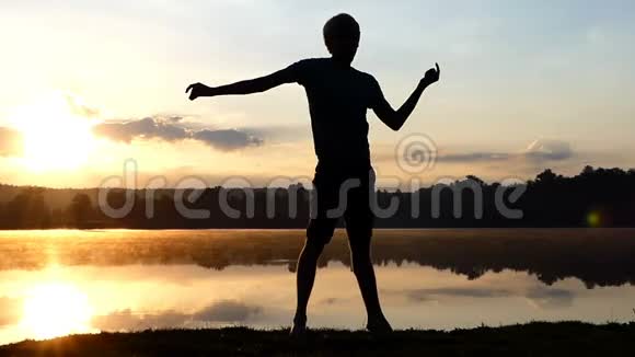 在日落时分一个虔诚的人在湖岸跳舞视频的预览图