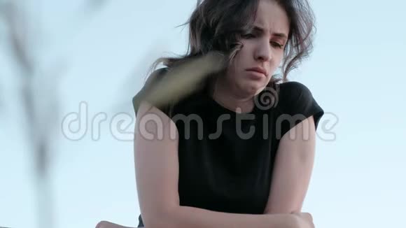 一个悲伤绝望的女孩交叉双手对着淡蓝色的天空哭泣视频的预览图