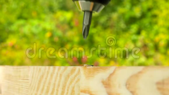 电动螺丝刀的特写在木板上拧下黑色自攻螺栓户外视频的预览图
