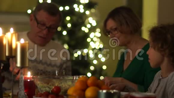 烛光晚餐爷爷把沙拉和鸡腿放在孙子盘子里感恩节视频的预览图