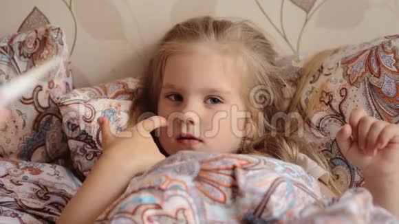 生病的小女孩躺在床上母亲检查她生病的女儿的口腔温度视频的预览图