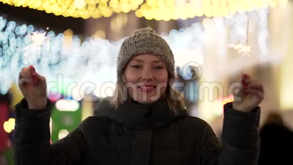 一个手里拿着火花的女孩圣诞卡明亮的冬天背景金色的灯光美丽的年轻女子视频的预览图