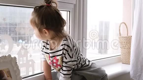 一个小女孩坐在窗台上猫从地板上看着她视频的预览图