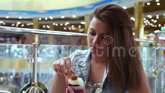 一个漂亮的女孩在咖啡馆里坐在桌子旁吃一个甜蛋糕视频的预览图