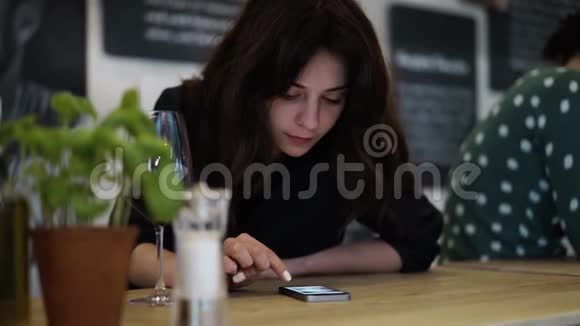 漂亮的黑发少女在德国咖啡馆用智能手机视频的预览图