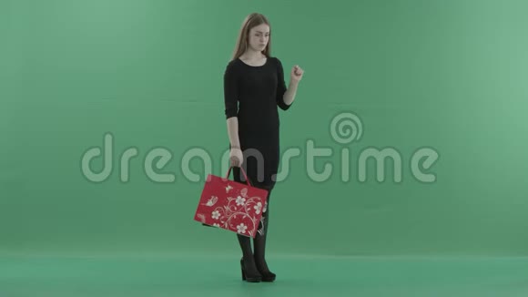 美丽的女人穿着黑色的小连衣裙手里拿着购物袋在数字屏幕上滚动她站在视频的预览图