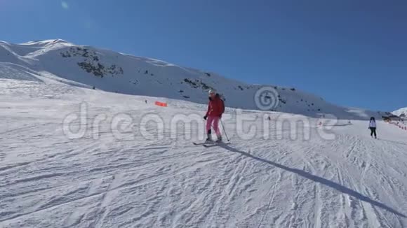 滑雪者在冬季阳光明媚的一天沿着山坡滑雪视频的预览图