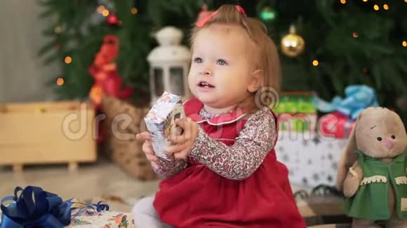 可爱的小女孩给父母送圣诞礼物坐在圣诞树旁特写视频的预览图