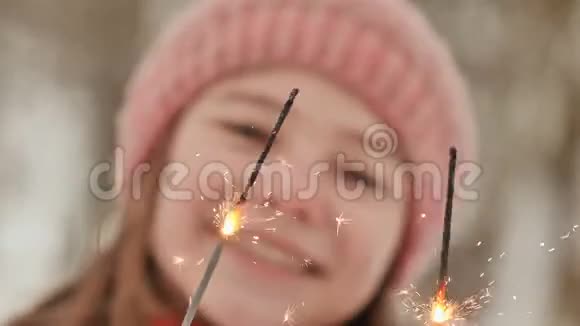 一位迷人的女学生手中闪烁着孟加拉灯的火花面对特写镜头自然森林在视频的预览图