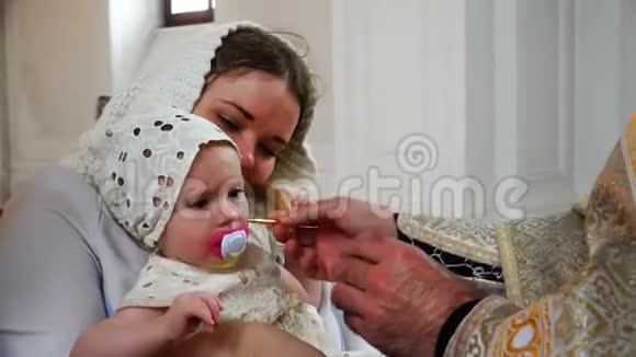 圣父用教堂的油抹上他的前额把手给婴儿视频的预览图