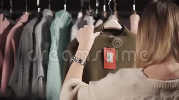 一位年轻女士正在考虑一件暖和的毛衣上面有一个标价的标签视频的预览图