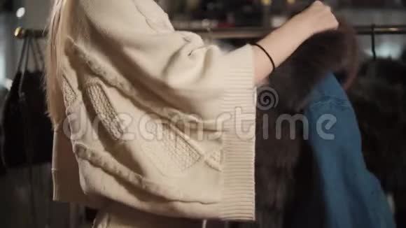 苗条的女人正在商店里试穿一件带毛皮的牛仔夹克视频的预览图
