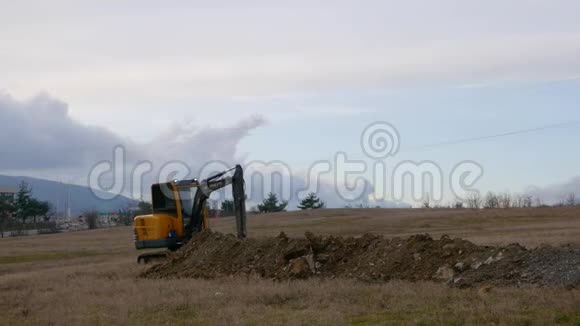 拖拉机挖掘机在田野中的神奇景观在无边无际的蓝天下挖沟视频的预览图