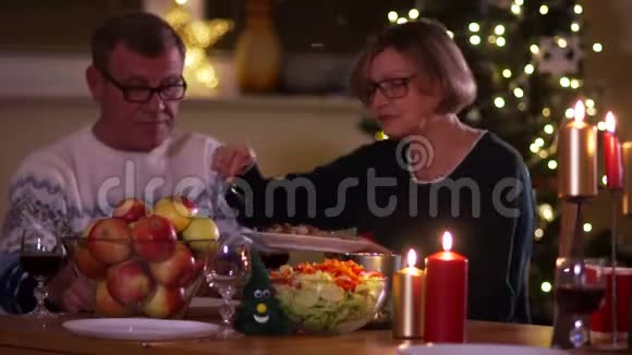 圣诞节的家庭晚餐感恩节时年长的夫妻正坐在餐桌旁女人把食物放在男人身上视频的预览图
