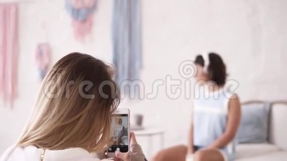 背面的镜头一个女孩为她的女性时尚朋友拍照女孩们在一起出去玩女孩们视频的预览图