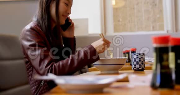 女人一边吃面一边用手机说话视频的预览图