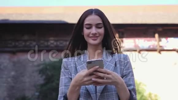 美丽的微笑女人用电话走在城市街道上视频的预览图