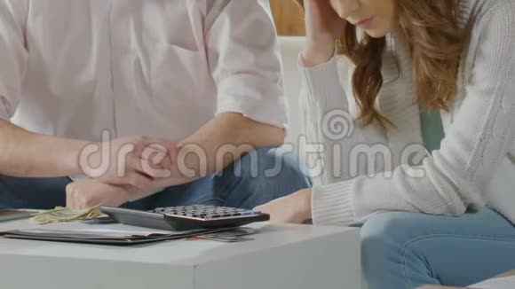 一对夫妇坐在桌子旁身上带着点钱一对女的头靠在手上债务缠身视频的预览图