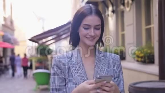 美丽的微笑女人用电话走在城市街道上视频的预览图