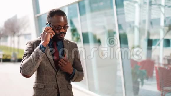 一个非洲裔美国人打电话给一个站在办公室中心附近的人视频的预览图