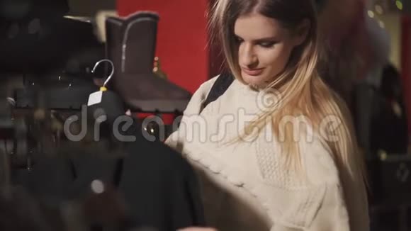 独身的女人在一家设计店里穿着衣服在衣架上检查衣服视频的预览图