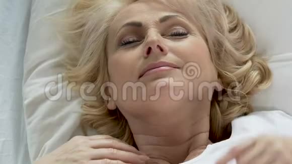 躺在床上的老年女士睡得好后揉着脸晚上的奶油化妆品视频的预览图