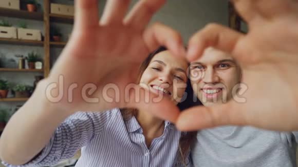 慢镜头描绘幸福的多民族夫妇用手做心看着相机微笑浪漫浪漫视频的预览图