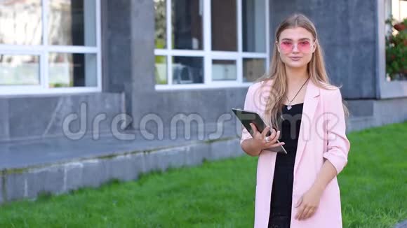 年轻的金发女郎在城里做平板电脑女性在街上使用无线互联网移动通信概念视频的预览图