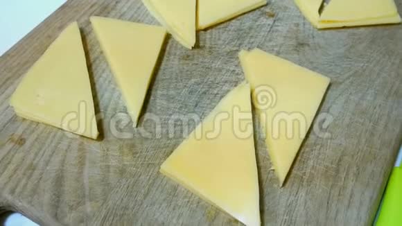 奶酪切成三角形的薄片躺在木制的厨房板上视频的预览图