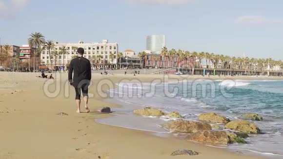 巴塞罗那一个穿着衣服的人走在冰冷波浪的海面上视频的预览图