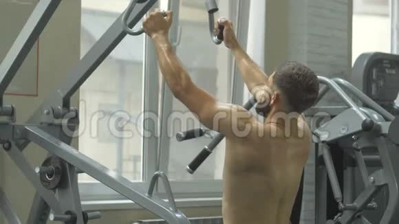 一个赤裸躯干的年轻人在健身房锻炼体格锻炼手部肌肉这一过程视频的预览图