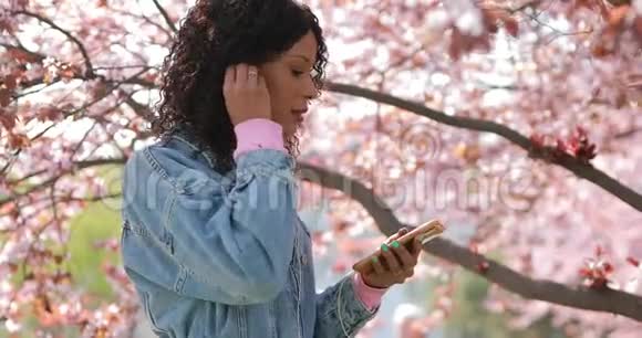 春天多种族的女人在公园里听音乐视频的预览图