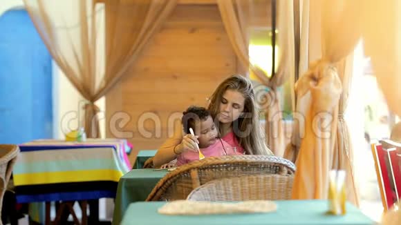 年轻的母女在咖啡馆里吃饭女儿喝柠檬水视频的预览图