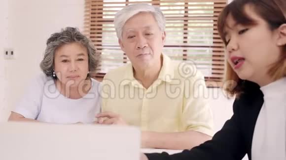 亚洲智能女性代理商通过文件平板电脑和笔记本电脑为老年夫妇提供健康保险老年亚洲夫妇咨询视频的预览图