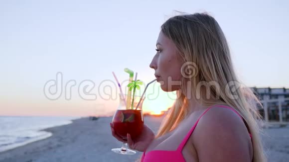 女孩在日落时喝鸡尾酒在水边聚会年轻时的肖像视频的预览图