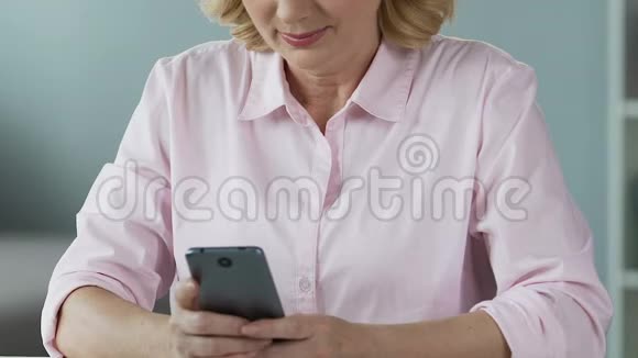 50多岁的女性在智能手机社交网络上滚动新闻特写视频的预览图