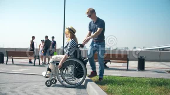 一个男人推着轮椅男人帮助坐轮椅的女人视频的预览图