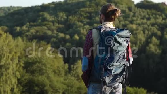 英俊的男人带着袋子旅行在大自然中徒步旅行视频的预览图