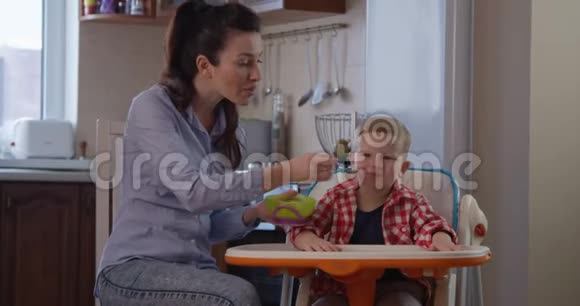 儿童坐在婴儿椅上与母亲一起吃食物视频的预览图