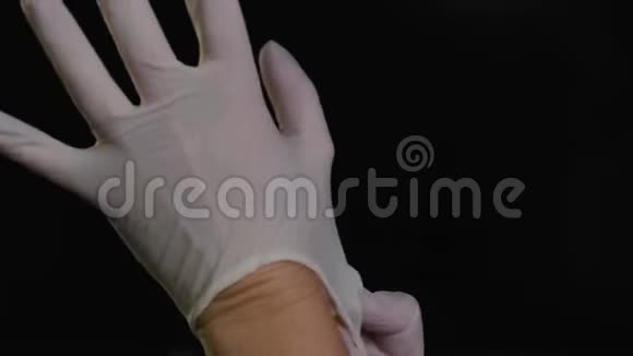 医生在黑色背景上戴上了白色防护手套视频的预览图