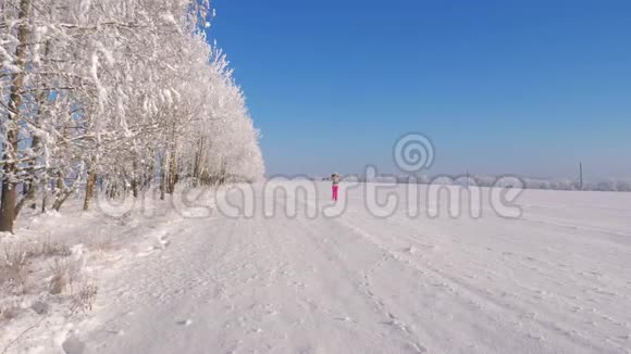 嬉戏的女人在冬天奔跑和旋转在田野的雪上手在一边视频的预览图