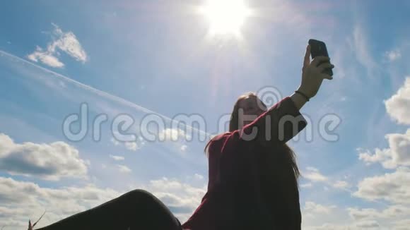 在蓝蓝的天空中微笑的年轻女子在大自然中自拍视频的预览图