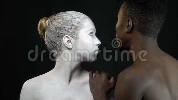 一个黑人男人微笑着而一个身着白色妆容的女人则显示出他背后的原因视频的预览图