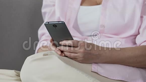 退休女性手持智能手机滚动屏幕方便移动应用视频的预览图