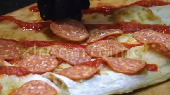 首席黑色硅胶手套制作美味的意大利披萨并在披萨面团上添加意大利香肠框架视频的预览图